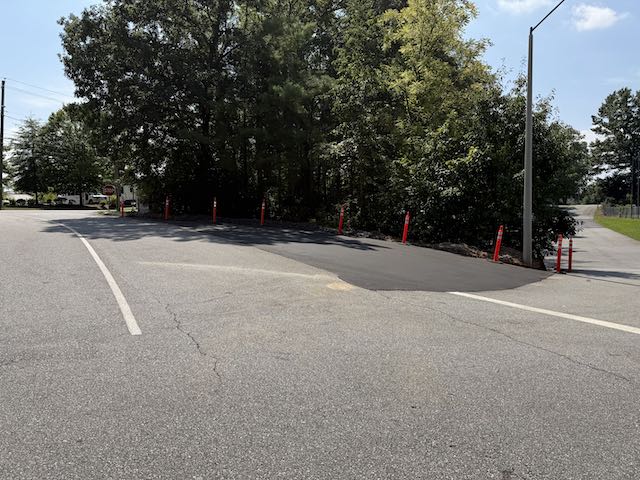Freshly paved, widened exit from the Estes Elementary campus onto Overlook Road with temporary orange delineators, August 2026