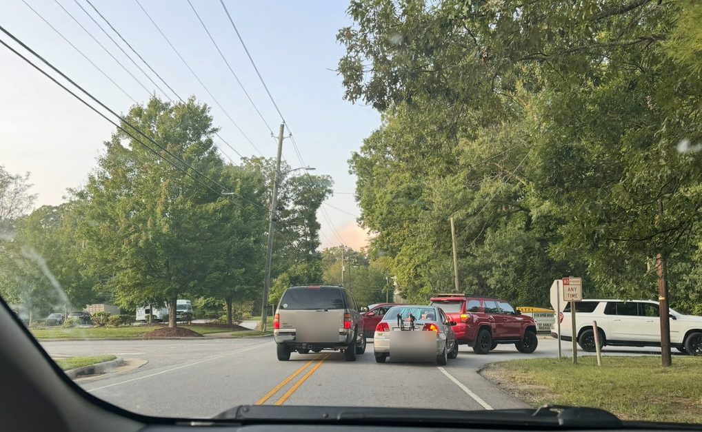 Two vehicles side by side on a two-lane section of Overlook Road, one on the wrong side of the double yellow line, near a No Parking Any Time sign