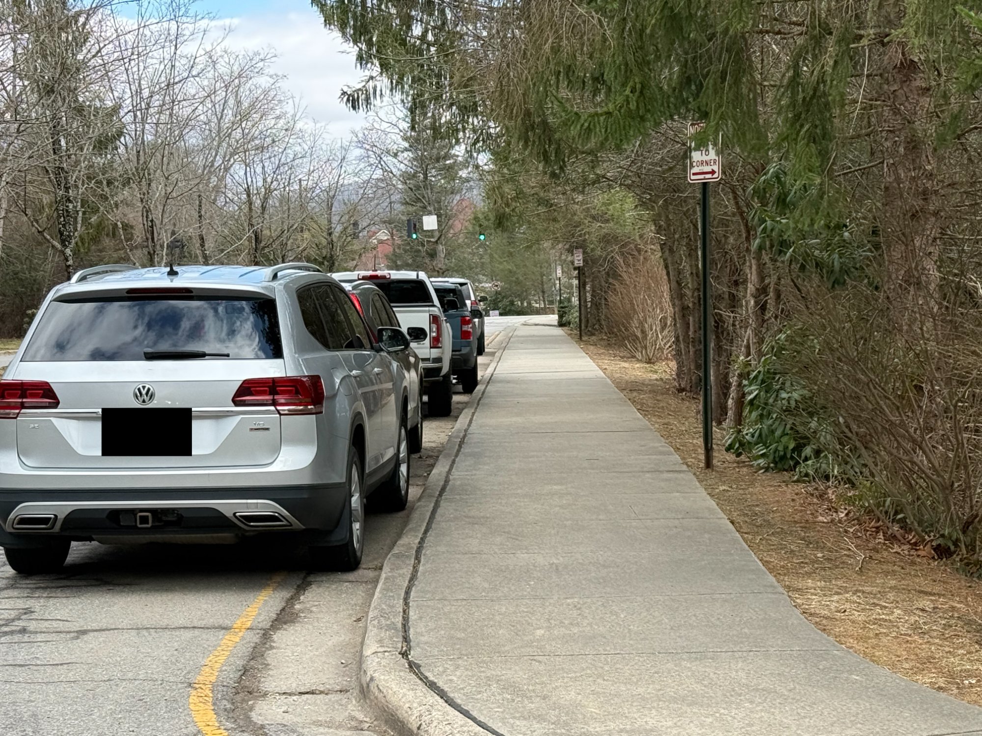 Cars parked along Pinchot Drive during school dismissal, with yellow no-parking zone visible at curb